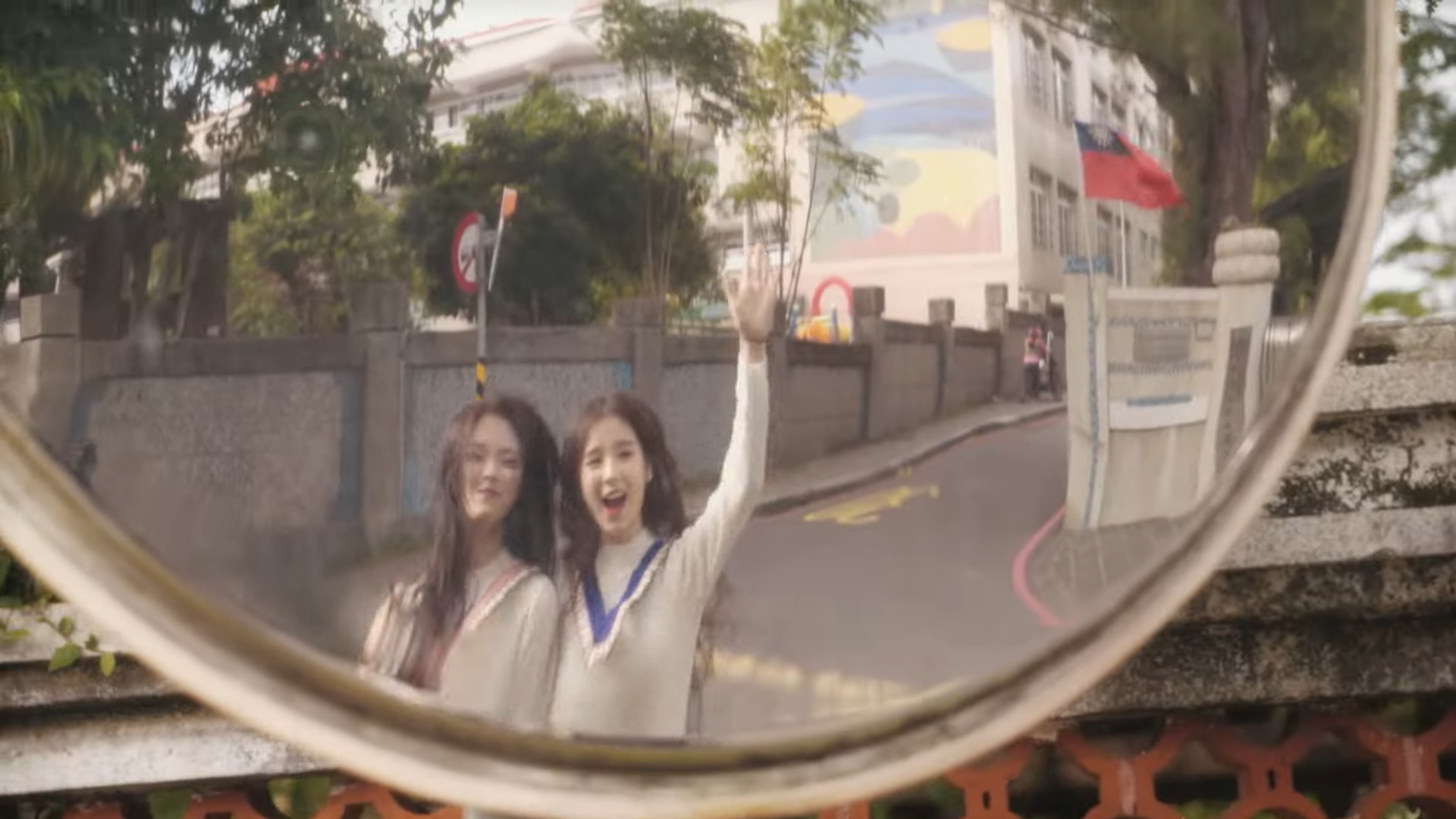 Heejin and Hyunjin reflected in a street mirror.
